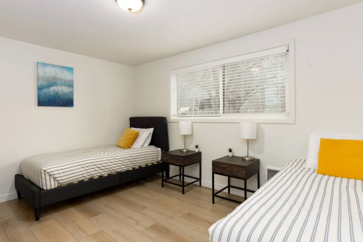 A tranquil room with two single beds, wall art, and nightstands with lamps. The bedding and overall decor create a cozy, inviting spot that feels both cheerful and comfortable for kids or friends sharing the space.