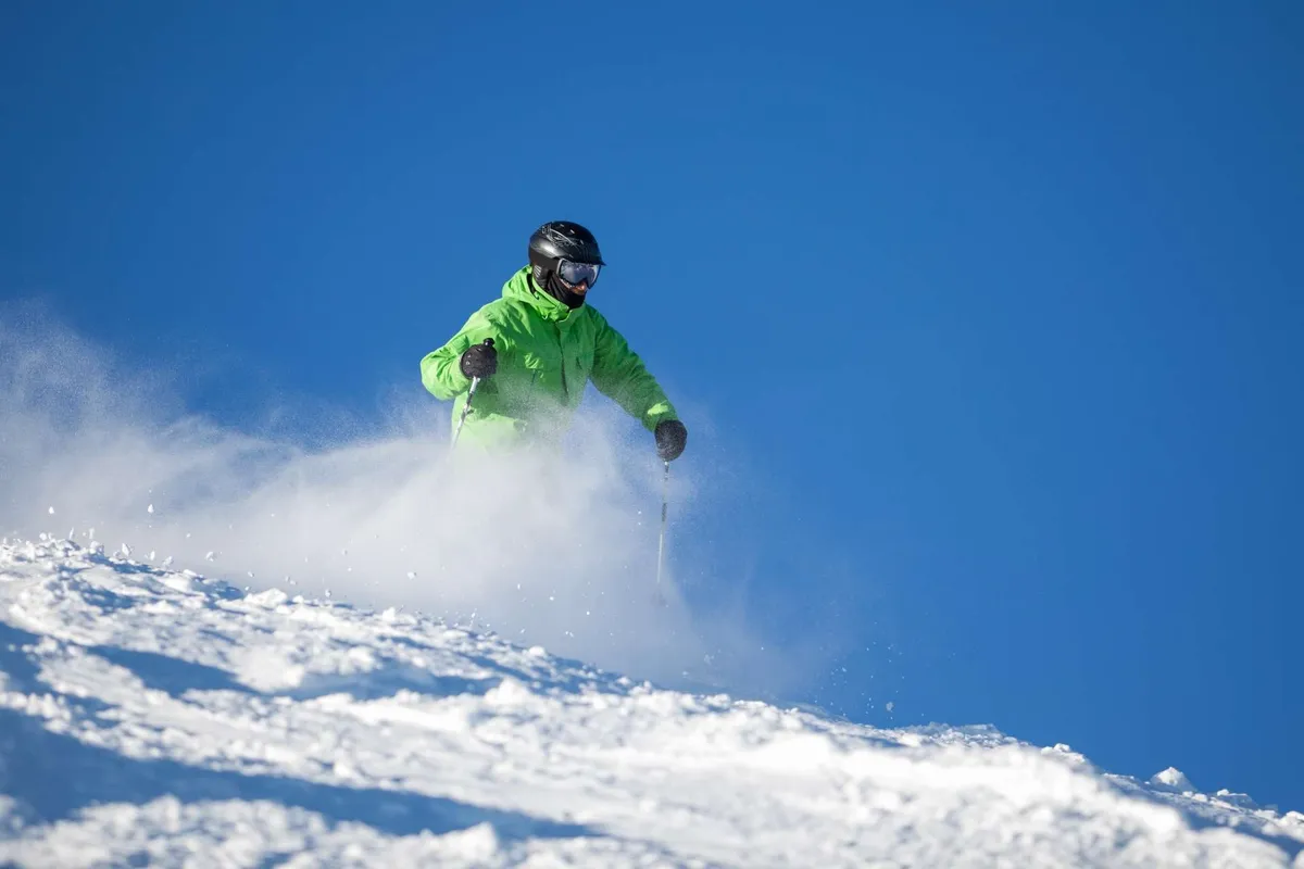 An exterior scene showcasing an active skier gliding through snow with a stunning mountain backdrop. The landscape is open and expansive, hinting at outdoor adventure and the natural beauty that defines the Bend area.